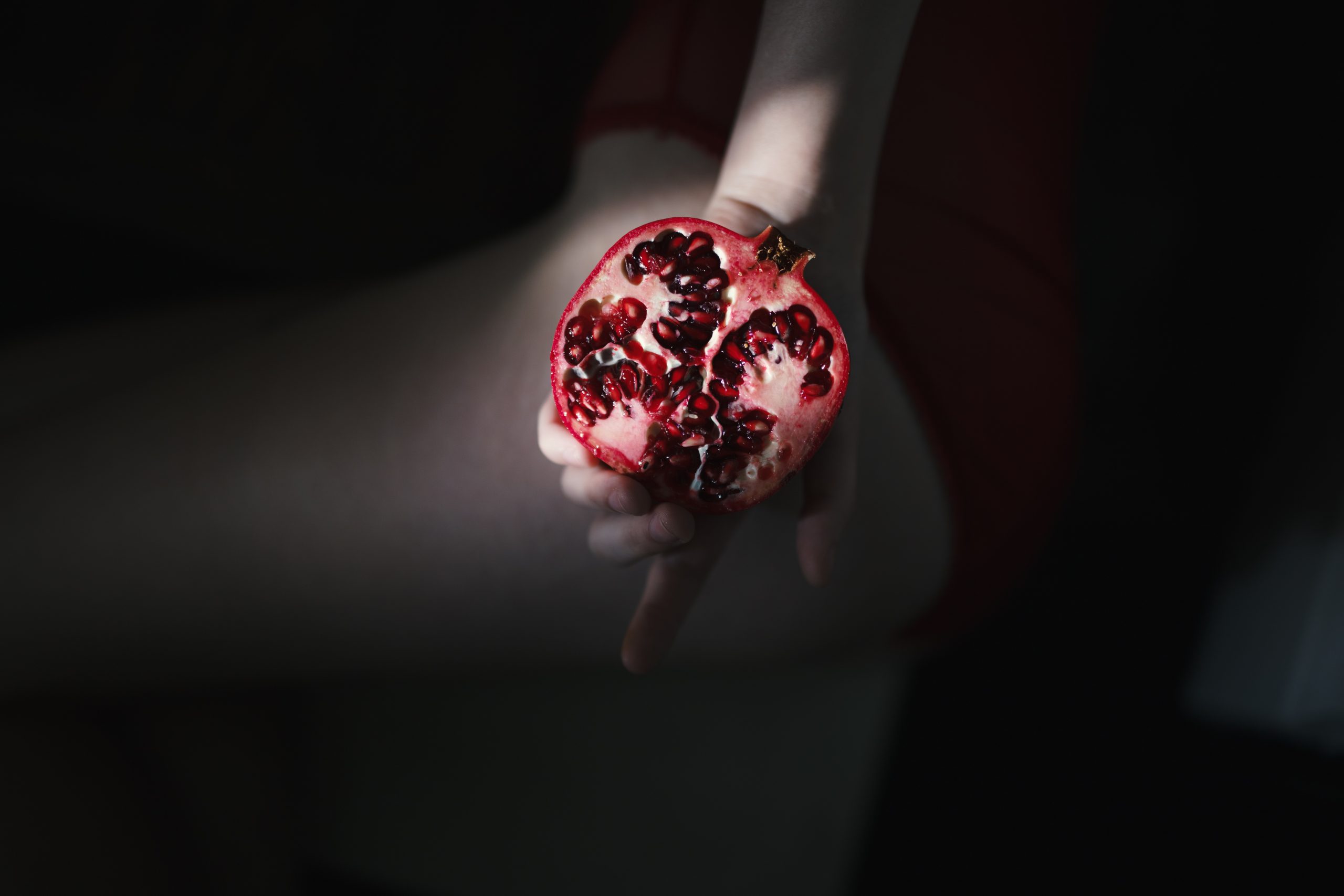 person holding red pomegranate